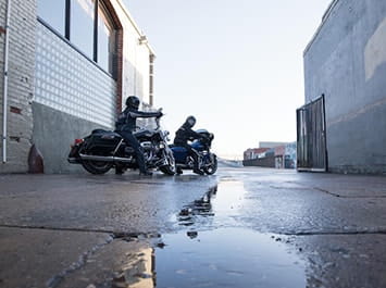Two motorcycles parked in a rain puddle