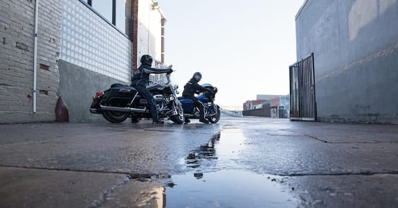 Two motorcycles parked in a rain puddle