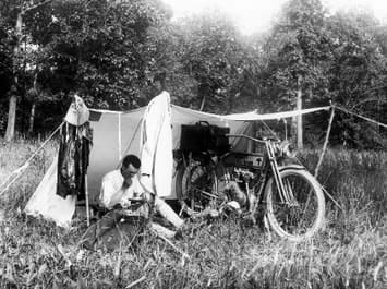 Black and white photo of someone camping with a motorcycle