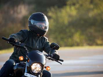 Someone riding a motorcycle wearing a black helmet